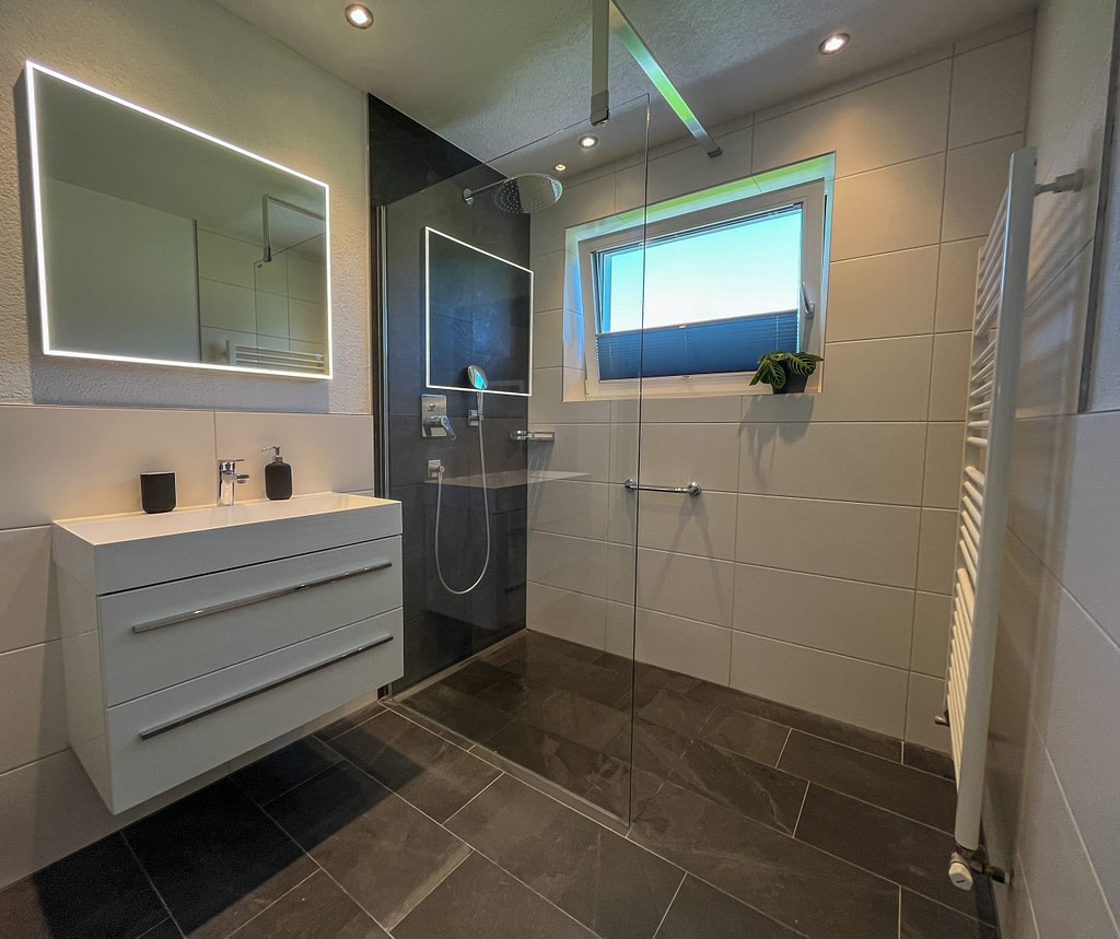 Home Modernes Badezimmer mit dunklen Fließen und Spiegel und Fenster