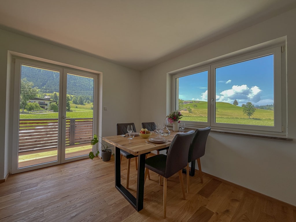 Home Heller Essbereich mit großem Fenster und Ausblick auf die Tiroler Berglandschaft in den AlpineHome Walchsee Apartments